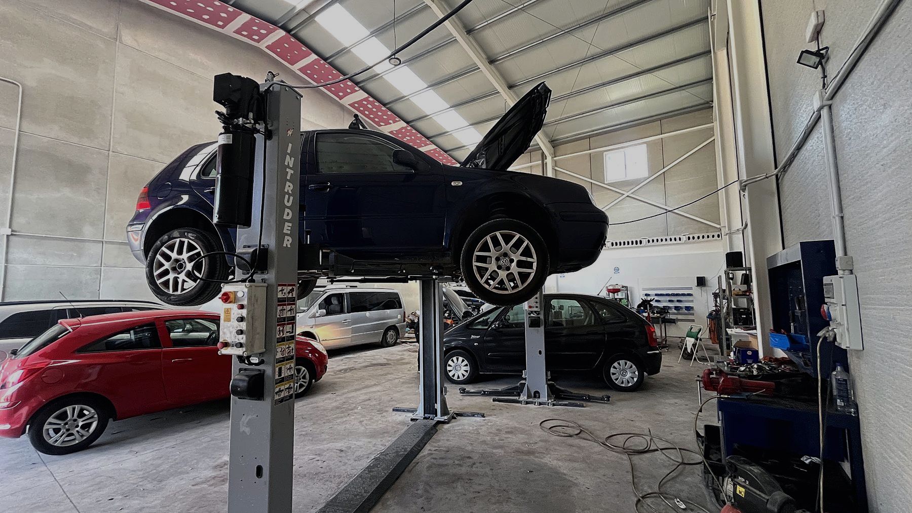 Un coche subido en el elevador de dos columnas dentro de la nave del taller