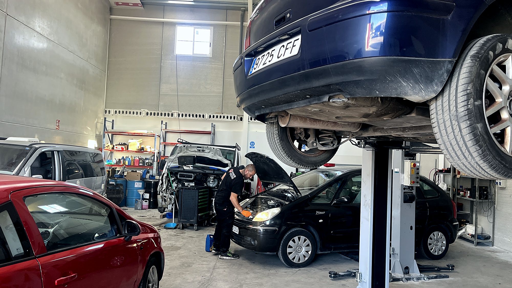 Un mecánico trabajando en el motor de un coche con el capó abierto
